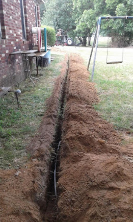 Freshly excavated sewer line trench across a Largo backyard